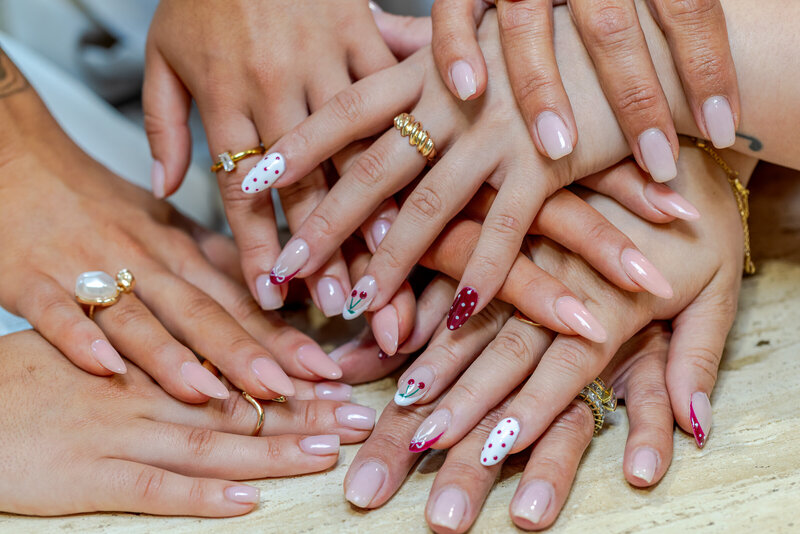 Several hands showing soft pink manicure examples